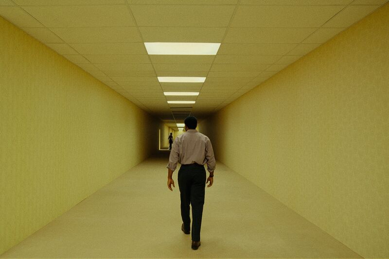 A man walks along a long corridor towards a spooky figure.