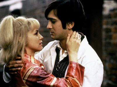 A young man and woman in 1960s fashion embrace