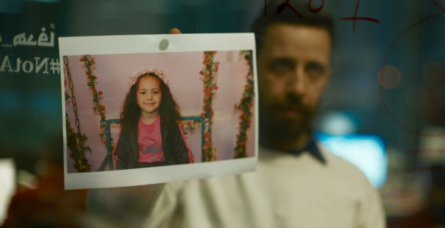 A man holds up a photograph of a little girl