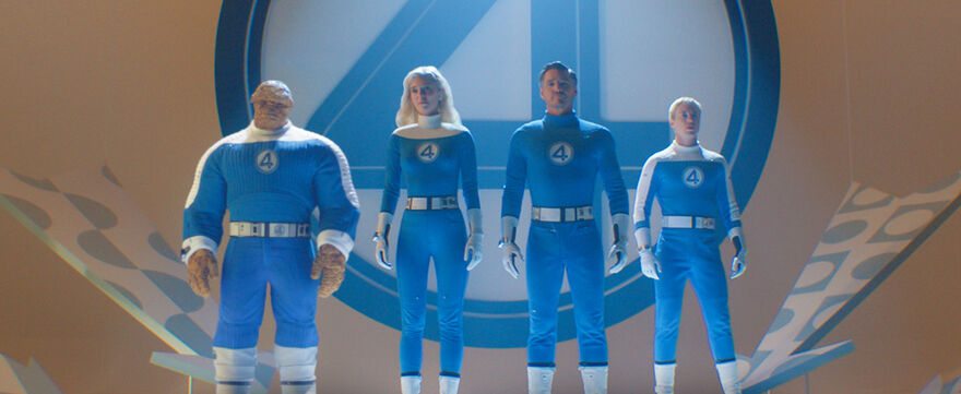 Three people and one man made out of rocks stand behind a giant number 4, all wearing blue suits with the number 4 on them.