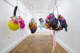 Colourful sculptures made from brightly coloured materials suspended from a gallery space 