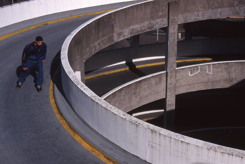 A person skates down a spiral road in a multi-story car park.