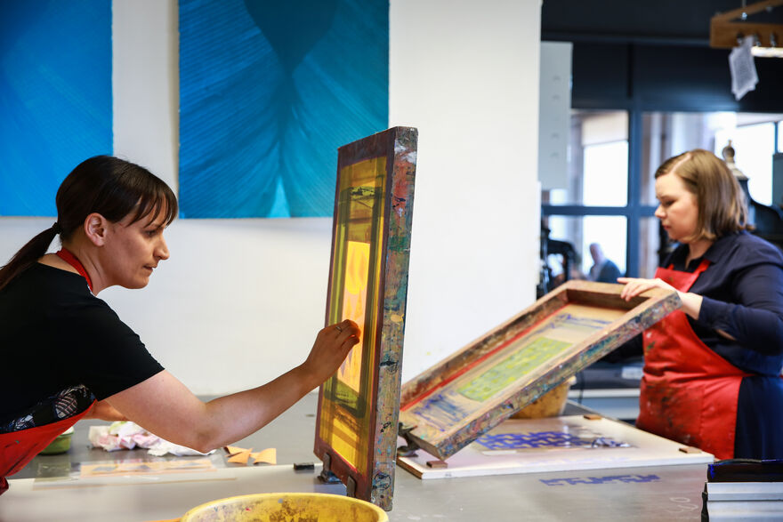 Two people doing screen printing in DCA Print Studio