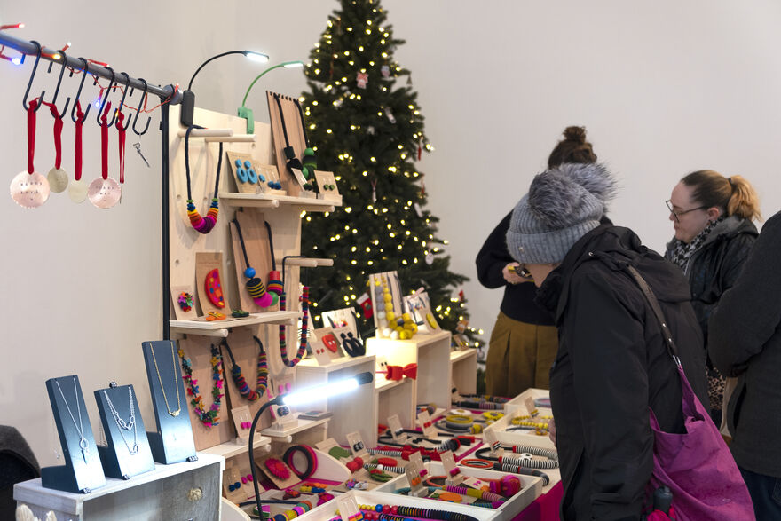 People browsing a stall at Crafted 2025 with a Christmas tree in the background