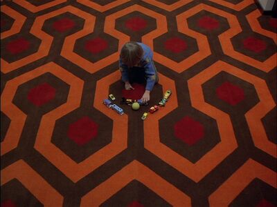 Child playing with toy cars on a patterned carpet