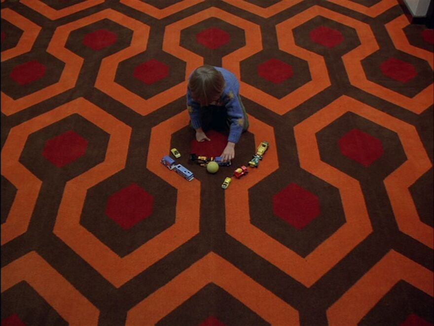 Child playing with toy cars on a patterned carpet