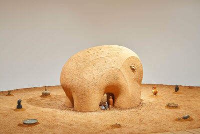 a large sculpture that looks as though it is made out of clay with some bottles underneath