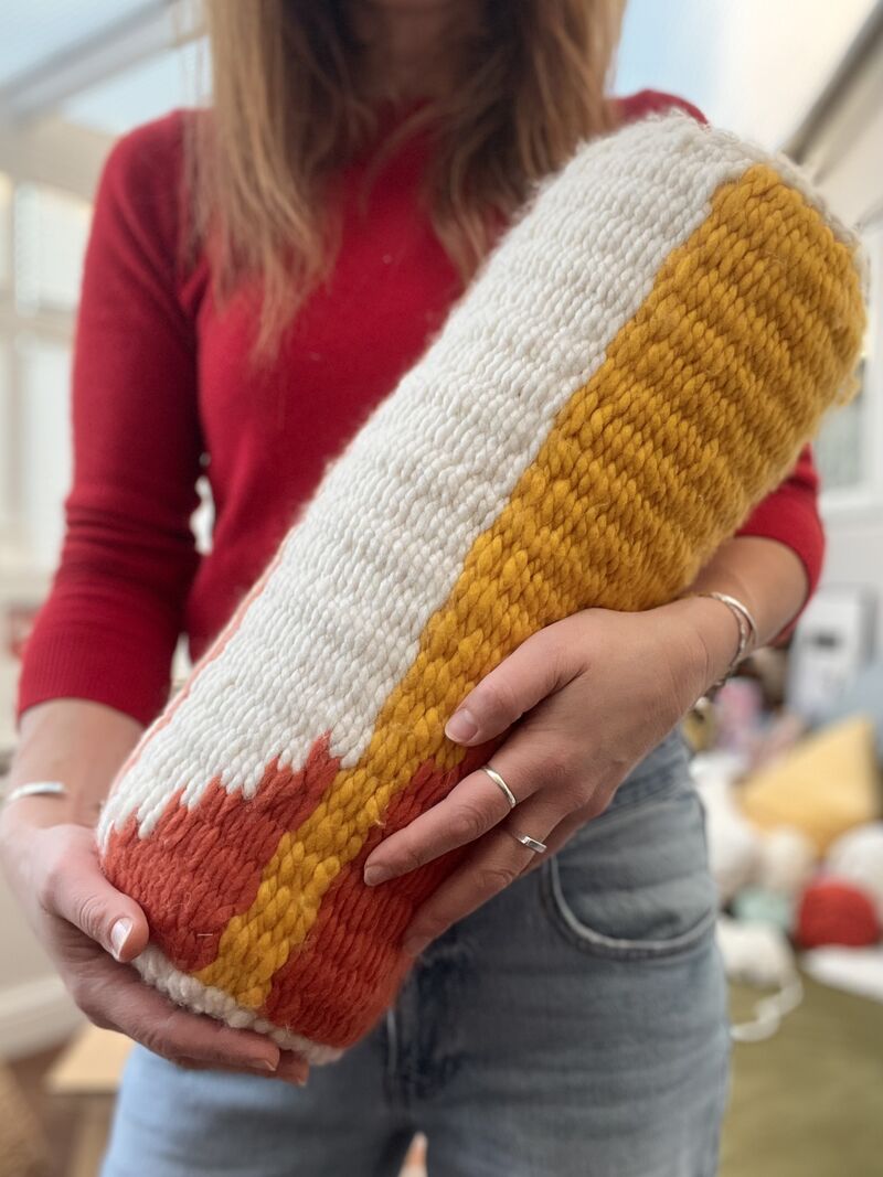 Person holding a woven bolster cushion