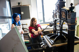 Person printing a lino cut using a printing press