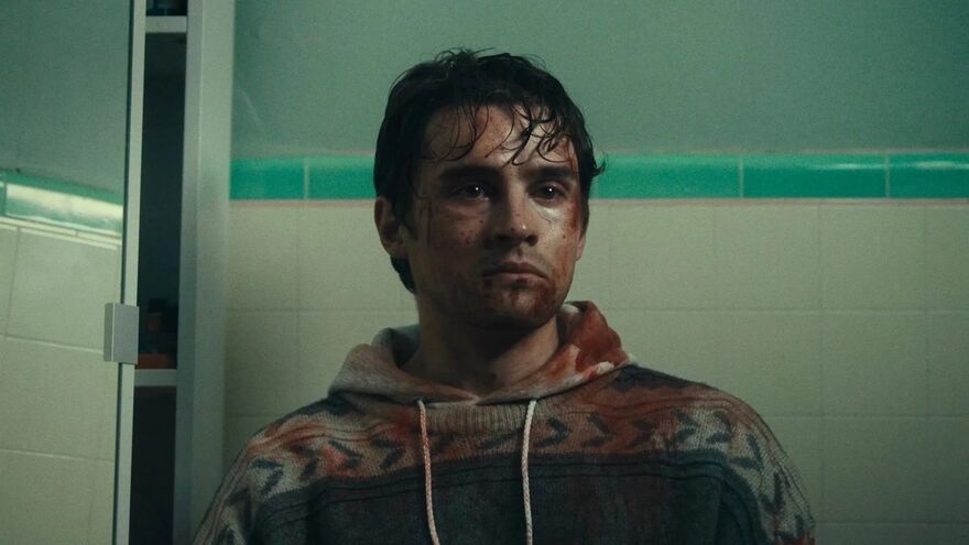 A bloodstained man looks forlornly forwards he appears to be in a bathroom