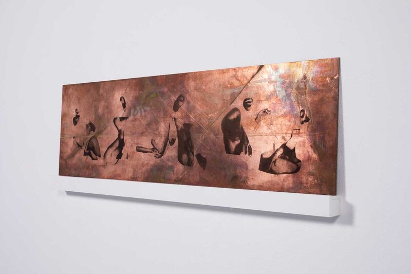 An artwork that looks like it is metal with images printed on it on a wall