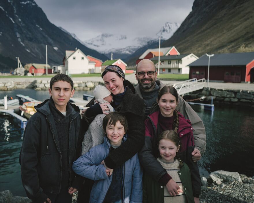 A family stand smiling in a rural landscape