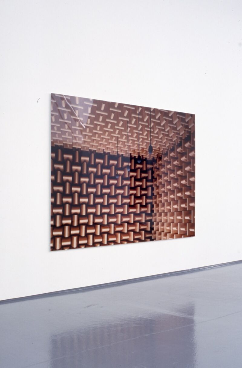 A large, black canvas with geometrical brown shapes on it.