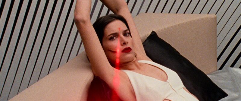 Woman holding her arms up as a red laser pointer points to her forehead