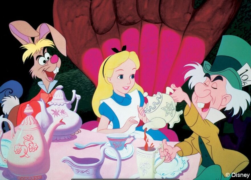 An animated still shows a little blonde girl enjoying a tea party with a rabbit and the mad hatter.