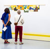People look at printed artwork at Claudia Martínez Garay's exhibition.
