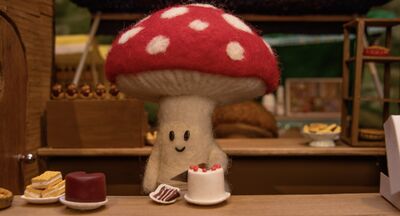A small felt mushroom cutting a slice of cake 