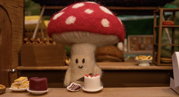 A small felt mushroom cutting a slice of cake 