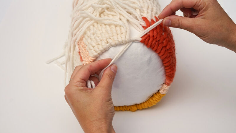Hands tying a knot while making a hand woven bolster cushion