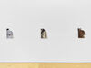 Embroideries of close ups mens clothing hang on a wall in a gallery space