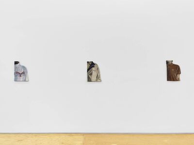 Embroideries of close ups mens clothing hang on a wall in a gallery space