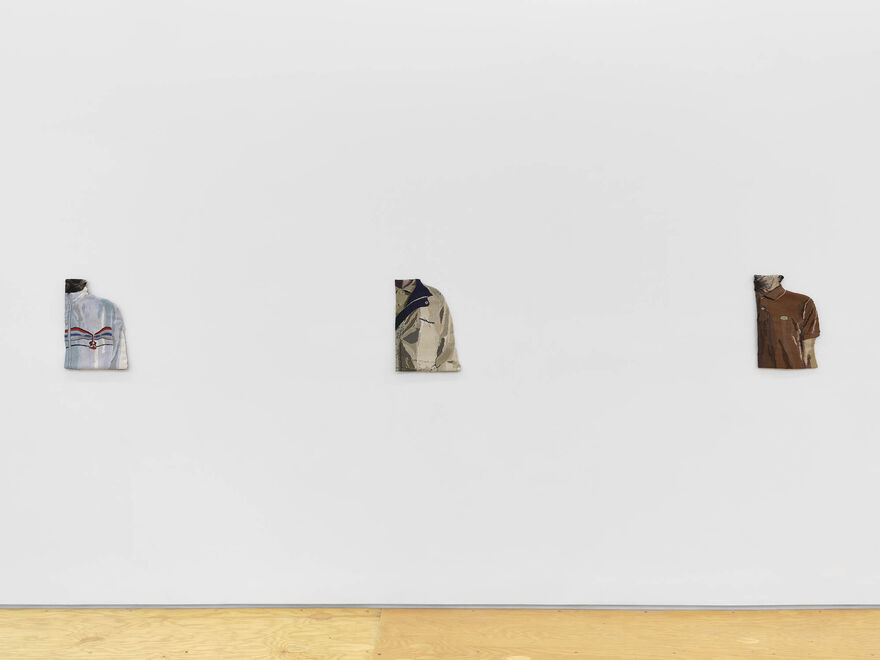 Embroideries of close ups mens clothing hang on a wall in a gallery space