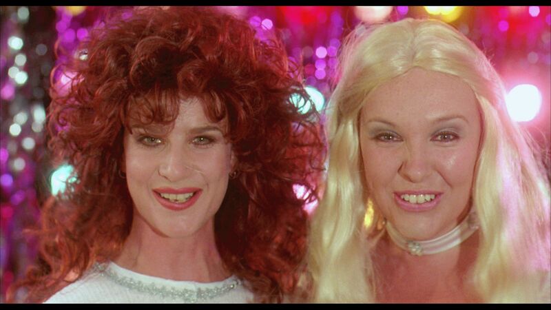 Two young women wearing wigs to make them look like ABBA smile.