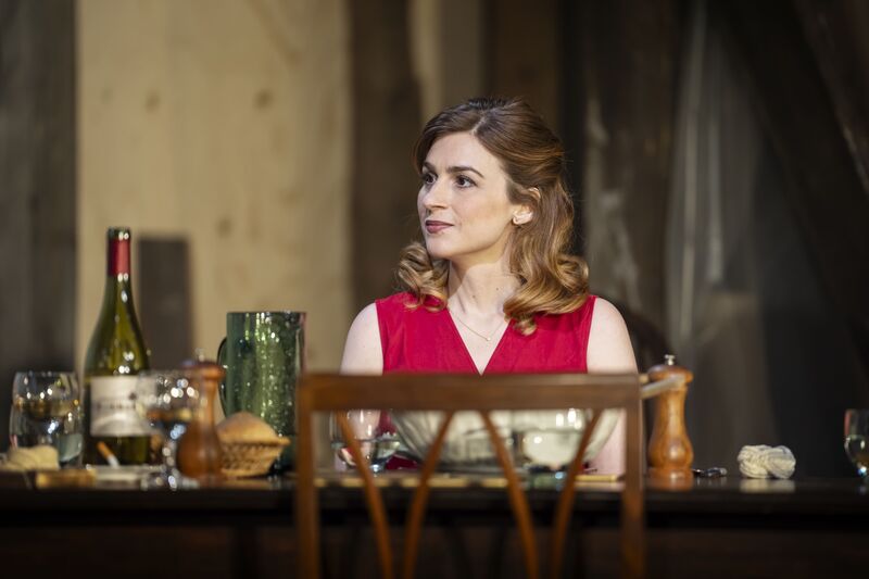 A woman in a red dress sits at a table.
