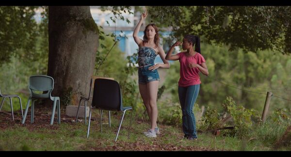 Two girls dance in a woodland area
