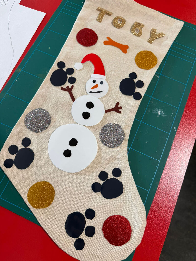 Stocing decorated with a snowman and paw prints and text saying TOBY