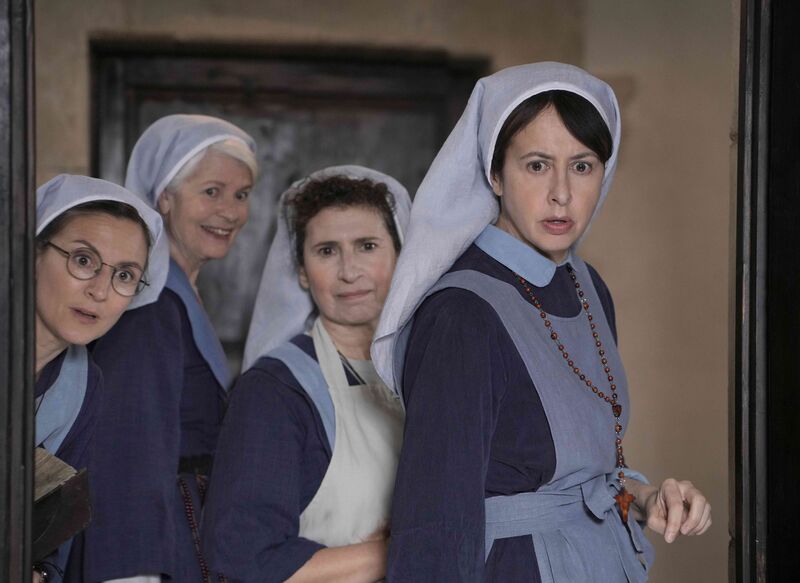 Four nuns peer round a door, two look shocked and one is smiling.