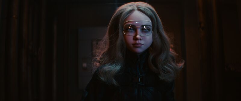A humanoid doll with blonde hair, wearing a transparent pair of goggles.