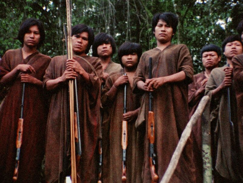 A group of indigenous Peruvian people stand holding rifles.