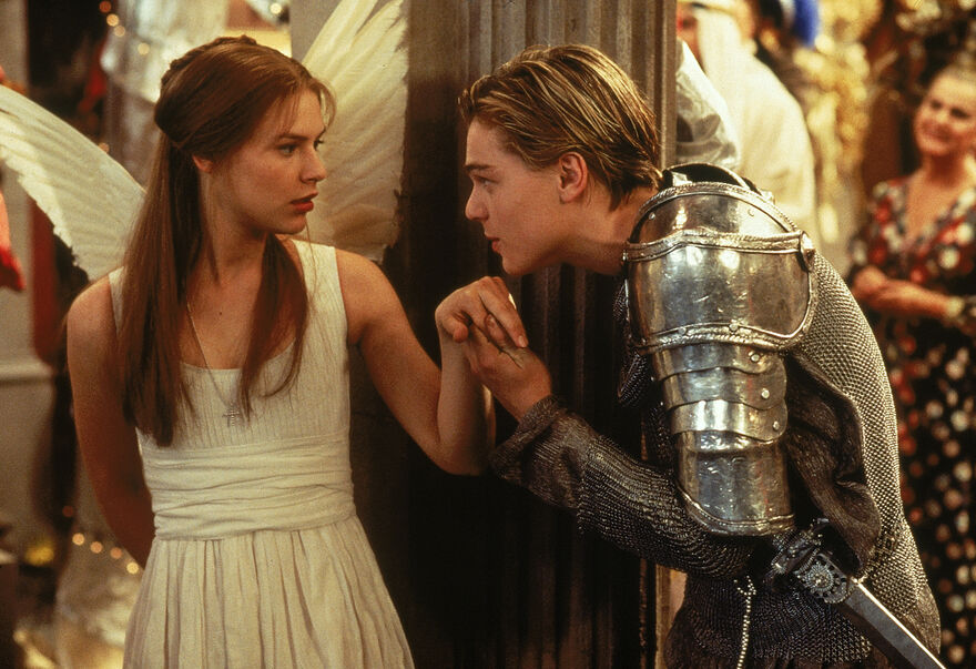 Romeo, dressed in armour, kisses Juliet's hand.