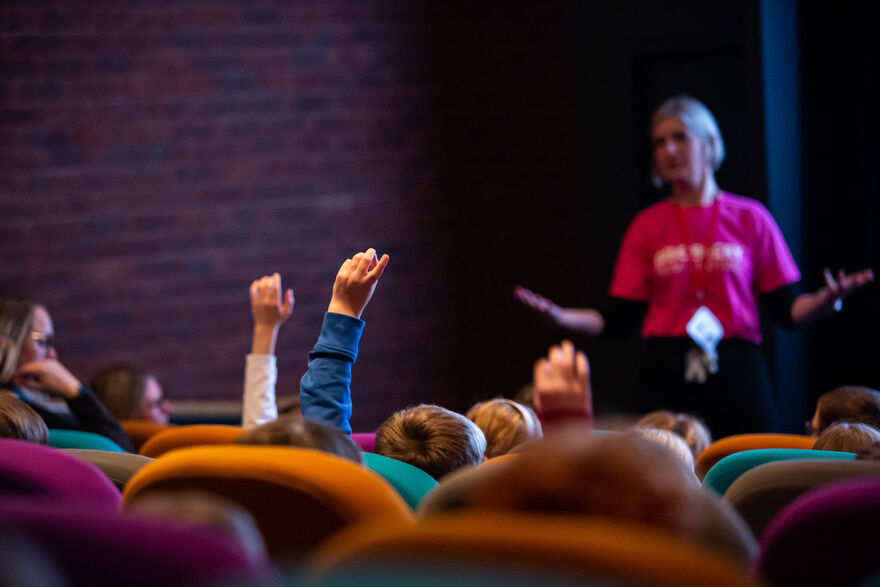 Children in the cinema, raising hands to answer a question
