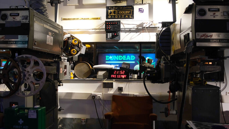 Projection booth with Dundead screen lide showing on the screen through the window