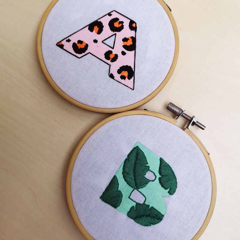 Two embroidery hoops woth printed letter designs embellished with embroidery