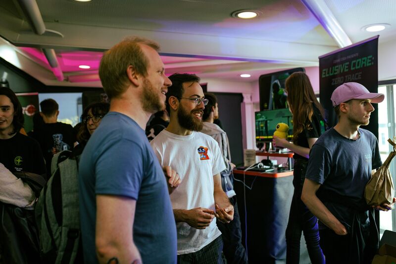 Two people smile and laugh together while watching others play games at Drop in and Play