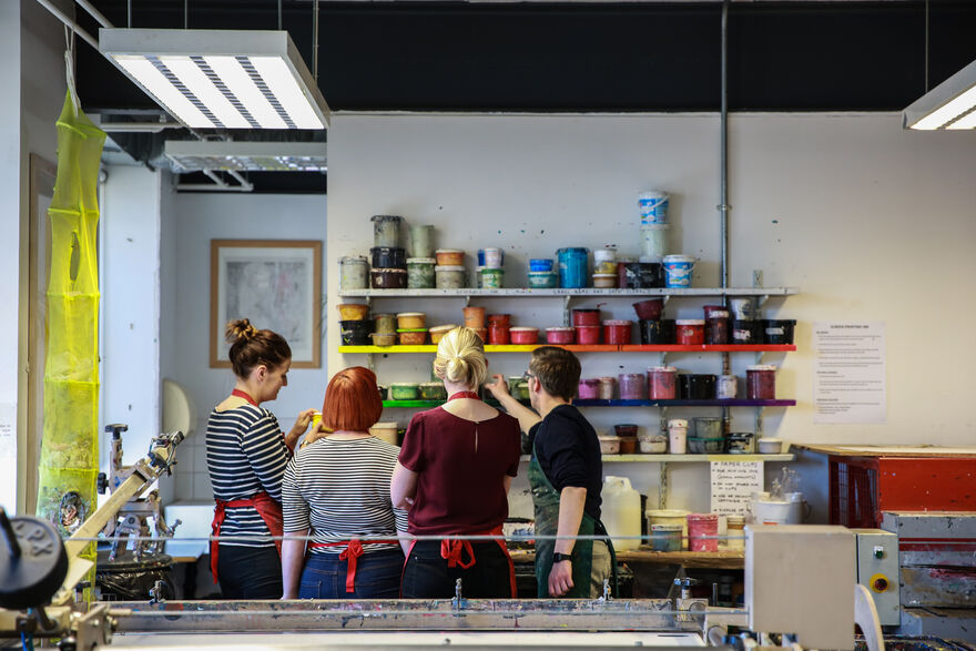A group of people choose paints in DCA Print Studio.