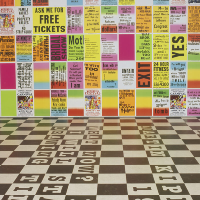 From Allen Ruppersberg's exhibition at DCA. The floors are black-and-white check, and there are bright, multicoloured graphic posters all over the walls with different slogan and sentences on them.