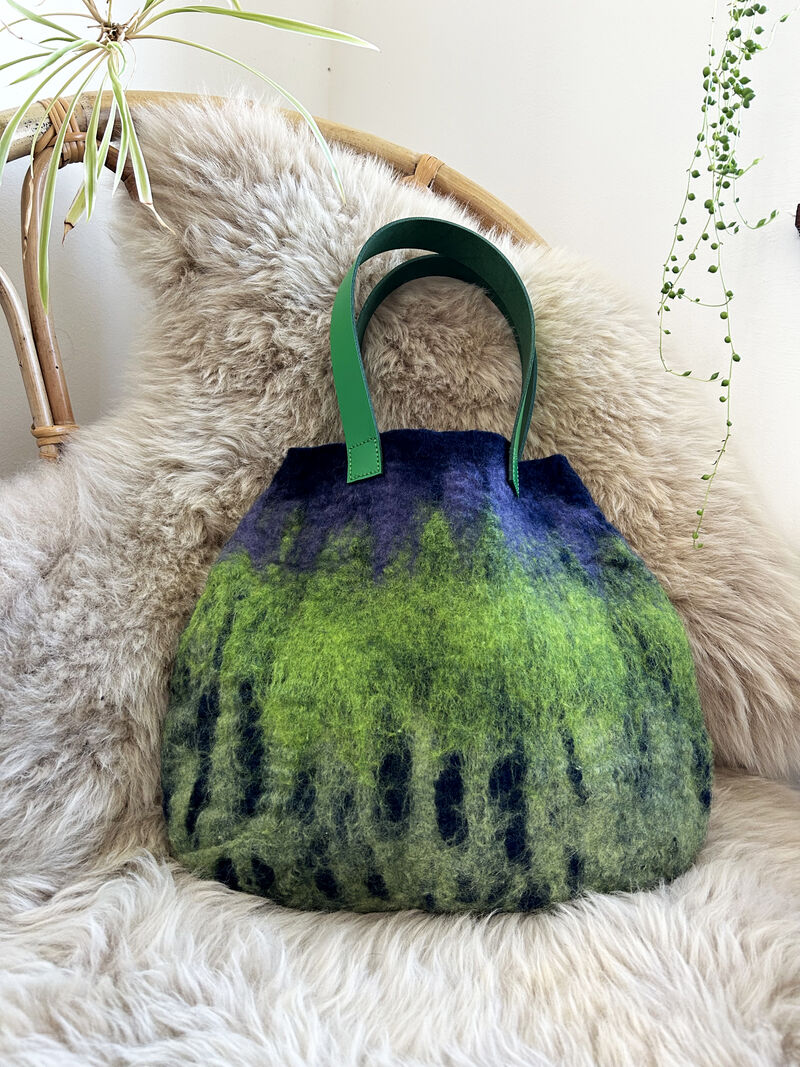 Green and blue felted handbag with green leather strap on a chair