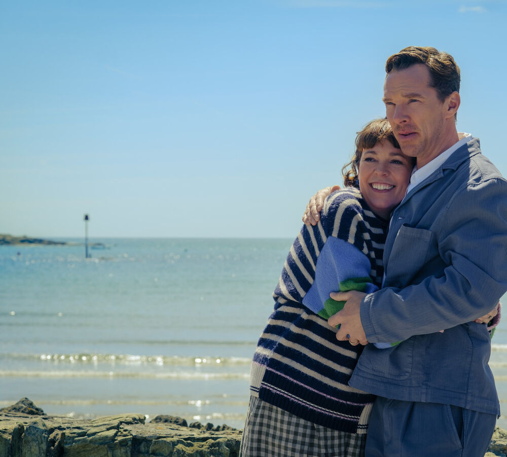 A man and woman embrace on a beach.