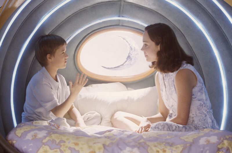 An android boy talks with his human mother in a cosy room. 