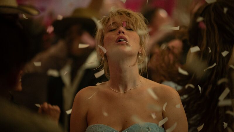 A blonde woman points her head up with her eyes closed while confetti lands on her