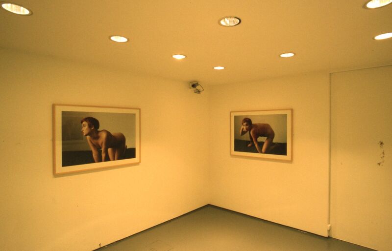 White gallery walls have framed photographs of a nude woman on them.