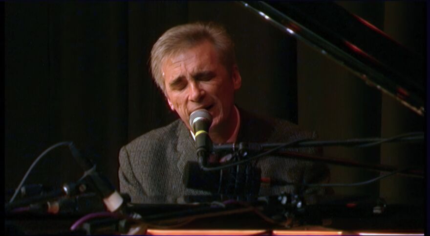 Michael Marra sings at a piano.