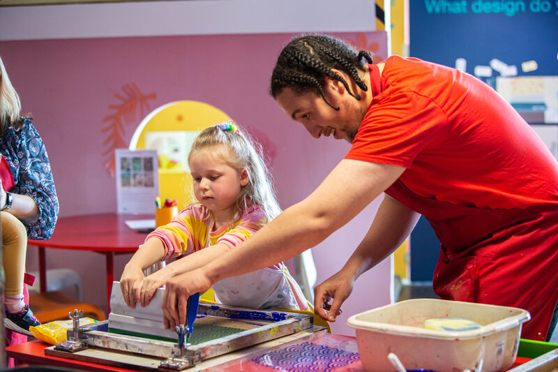 DCA Learning tutor helping a girl to pull a screen print