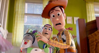 A sheriff toy (right) and an astronaut toy (left) are stood side by side with their arms pulled back in shock, they are in a bedroom. Woody is the sheriff and Buzz Lightyear is the astronaut.