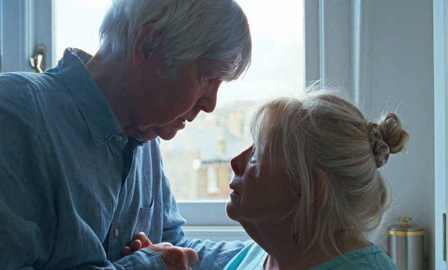 An older man and an older woman stare into each others' eyes