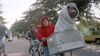 A boy in a red hoodie rides a bike with a cute alien in the basket